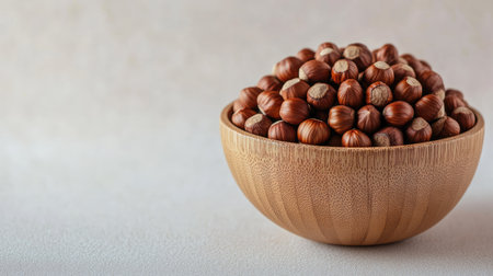 Healthy eating concept featuring raw hazelnuts in a wooden bowl, isolated on a light background, symbolizing natural nutritionの素材