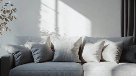 Living room interior design with a gray fabric sofa and white wall, pillows arranged neatly, sunlight creating a warm atmosphere, space on the left for creative useの素材