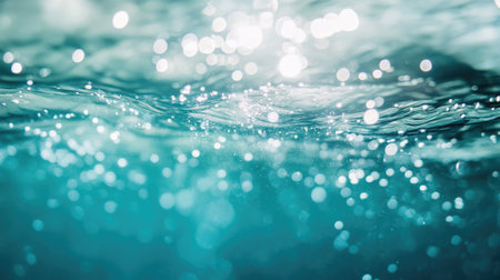 Blurry, clear blue water with small ripples and bubbles rising to the surface. Sunlight glistens on the water, creating an abstract, calming effect.の素材