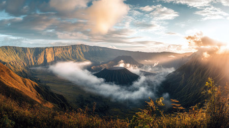 Panoramic view of Mount Bromo with mist covering the caldera and dramatic sunlight breaking through. A stunning natural landscape of East Java.の素材