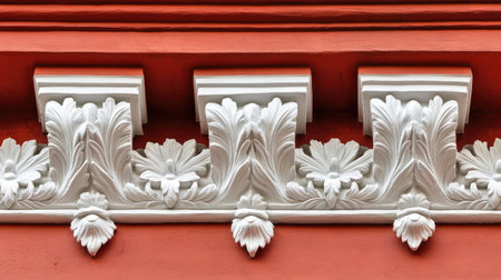 Close-up of a red brick wall with intricate white stucco designs, creating a beautiful architectural contrast.の素材