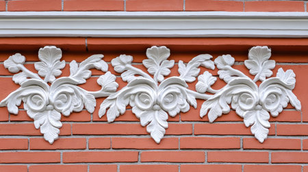 A brick wall with cladding, decorated with white stucco leaf and vine motifs, providing an ornate, classic look.の素材