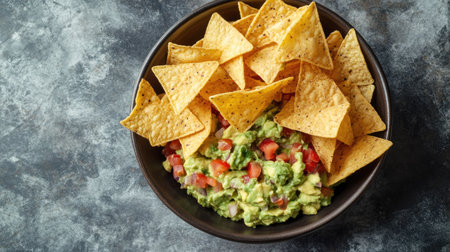 A mouthwatering bowl of guacamole with salted tortilla chips, beautifully arranged on a grey marble table. Perfect for snacking.の素材