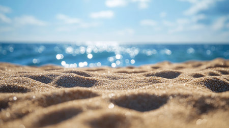 Close-up of smooth beach sand grains with the ocean horizon in the background, the water sparkling in the summer sun. Ideal for vacation or tropical themes.の素材