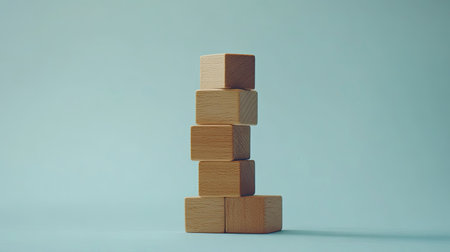 Stacked wooden blocks arranged as steps on a light blue background, representing growth and progress in business. Minimalist design with plenty of copy space.の素材