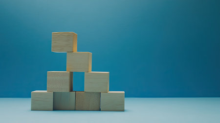 Wooden blocks stacked as steps on a blue paper background, symbolizing upward growth and achievement in business. Lots of copy space for business presentations.の素材