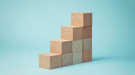 Wooden blocks in a stair formation on a light blue background, demonstrating a clear path to business growth. Plenty of empty space for promotional text or logos.の素材