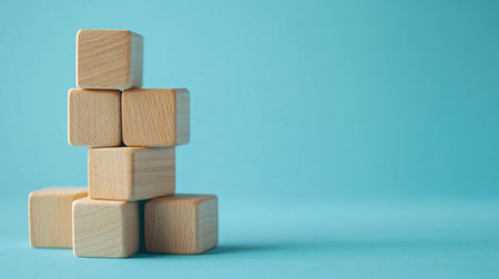 Wooden blocks stacked as steps on a blue paper background, symbolizing upward growth and achievement in business. Lots of copy space for business presentations.の素材