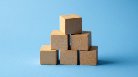 Wooden blocks stacked as steps on a blue paper background, symbolizing upward growth and achievement in business. Lots of copy space for business presentations.の素材