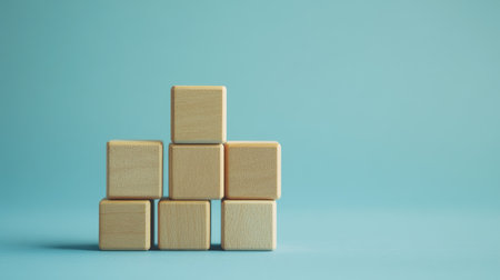 Wooden blocks stacked on a blue background, representing a business growth ladder. The minimalistic setup offers room for copy or branding elements.の素材