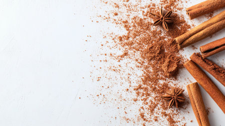 A collection of aromatic spices, including cinnamon and anise, scattered on a white surface, perfect for culinary use and food styling in various recipes.の素材