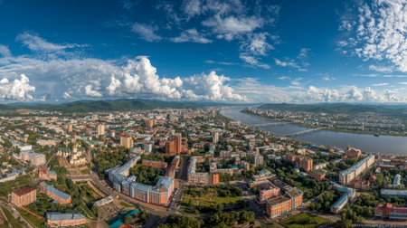 Explore a stunning aerial perspective of a city showcasing a beautiful river, lush greenery, and a backdrop of dramatic clouds under a bright sky.の素材