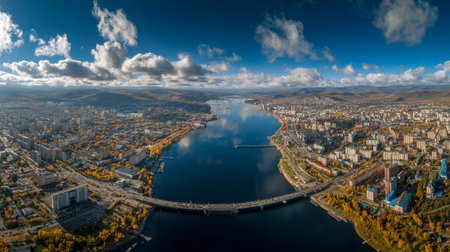 Stunning panoramic view of a city along a river, adorned with autumn foliage. A beautiful mix of nature and urban life, showcasing vibrant colors and reflections.の素材