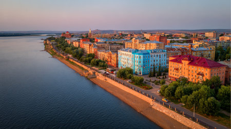 Captivating aerial view of a colorful city along a river at sunset. The vibrant architecture reflects in the calm water, creating a serene atmosphere perfect for exploration.の素材