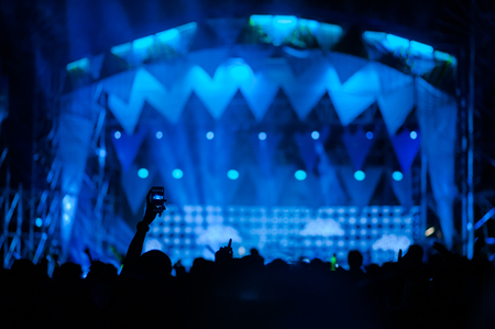silhouettes of concert crowd in front of bright stage lightsの写真素材
