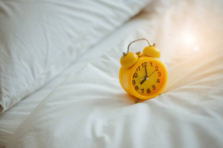 Closeup alarm clock  in bed after waking up, sunlight in morning.の写真素材