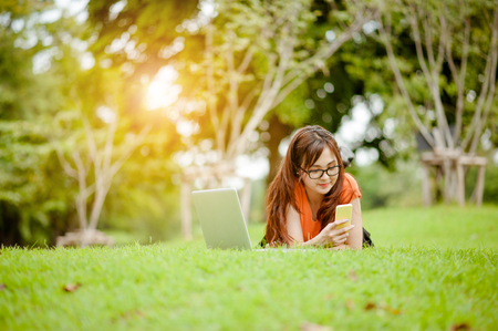 Young beautiful Asian woman working at outdoor park,happy relaxing. owner business woman work  at outdoor park.internet and technology concept.の写真素材