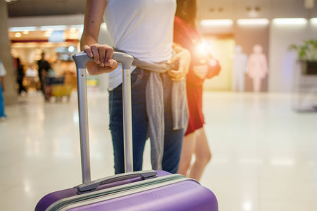 close up man hand touching baggage for check in at flight timetable in international airport.の写真素材