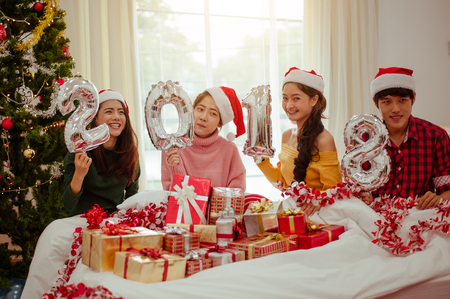 Happy New Year to you! Group of cheerful young people in Santa hats carrying silver colored numbersの写真素材