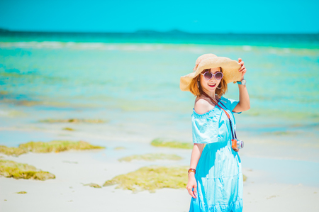 summer holidays, vacation, travel and people concept - smiling young woman in sun hat on beach over sea and blue sky background.copy spaceの写真素材