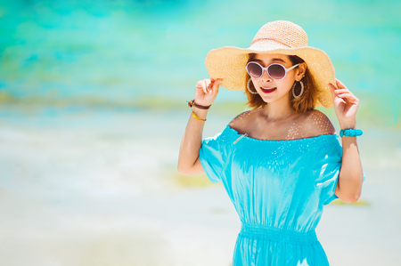 summer holidays, vacation, travel and people concept - smiling young woman in sun hat on beach over sea and blue sky background.copy spaceの写真素材