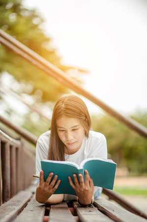 Beautiful young brunette woman lying on the amphitheater with a book in her hands. Romantic outdoor conception.の写真素材