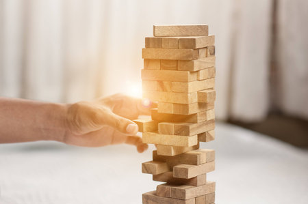hand  pulling out or placing wood block on the tower in modern office. plan and strategy in business. blur for background.の写真素材