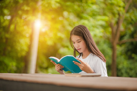 Asian girl reading book at park in summer sunset light. asian woman reading book in Thailand. asian...