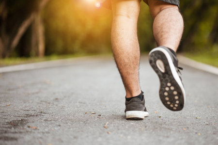 Close up shot of runner's shoes.A person running outdoors on a sunny day. Only the feet are visible. The person is wearing black running shoes.fitness and healthy lifestyle.Walking on a running track.の写真素材