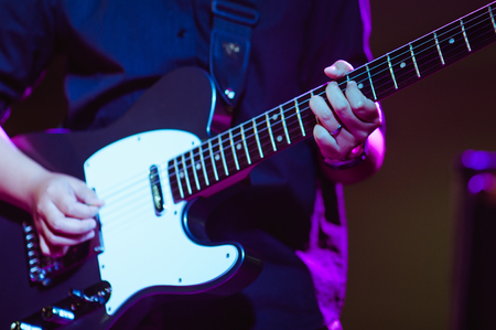 man playing guitar on a stage musical concert close-up view.guitarist plays.
