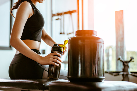 Relaxing after training.beautiful young woman looking away while sitting  at gym.young female at gym taking a break from workout.woman brewing protein shake.の写真素材