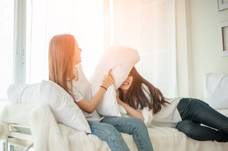Women at pillow fights in bedroom.の写真素材