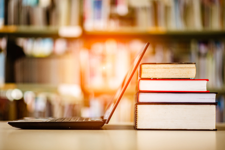 Bookshelves and laptops are placed on the library desk.の写真素材