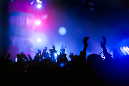 silhouettes of hand in concert.Light from the stage.confetti.the crowd of people silhouettes with their hands up.ribbonの写真素材