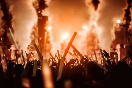 silhouettes of hand in concert.Light from the stage.confetti.the crowd of people silhouettes with their hands upの写真素材