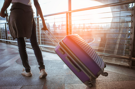 Young woman pulling suitcase in  airport terminal. Copy spaceの写真素材