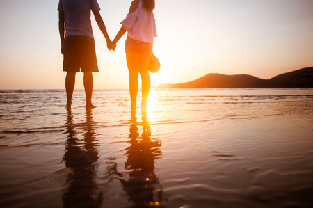 happy couple running to the sea at sunset beach.の写真素材