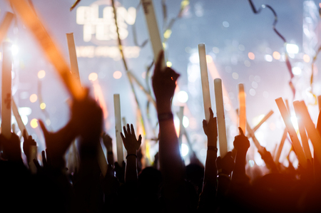 silhouettes of hand in concert.Light from the stage.confetti.the crowd of people silhouettes with their hands up.ribbonの写真素材