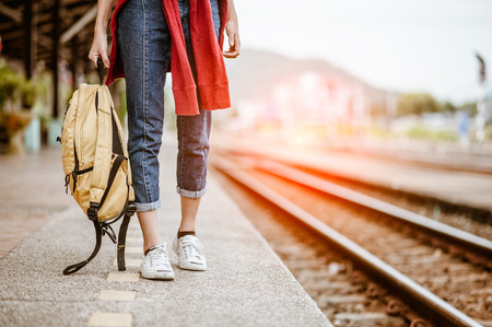 Close Up of A woman's legs are waiting for the train at the train station with her backpack.の写真素材