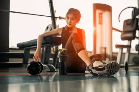 Relaxing after training.beautiful young woman looking away while sitting  at gym.young female at gym taking a break from workout.の写真素材