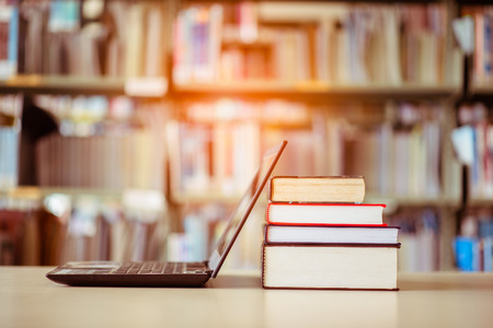 Bookshelves and laptops are placed on the library desk.の写真素材