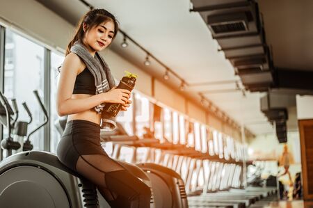 young fitness woman tired in gym drink   protein shake.exercising concept.fitness and healthy lifestyleの写真素材
