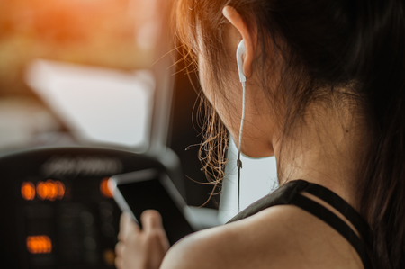 Fitness woman is choosing music to run on a treadmill.exercising concept.fitness and healthy lifestyle.の写真素材