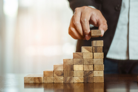 plan and strategy in business.risk concept.hand of man has piling up and stacking a wooden block.Businessman Building The Success.の写真素材