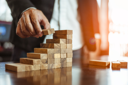 plan and strategy in business.risk concept.hand of man has piling up and stacking a wooden block.Businessman Building The Success.の写真素材