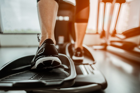 Closeup leg of cardio workout on an elliptical.people working out on an elliptical trainer in gym.Back viewの写真素材