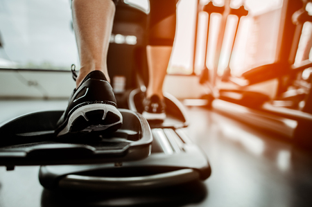 Closeup leg of cardio workout on an elliptical.people working out on an elliptical trainer in gym.Back viewの写真素材
