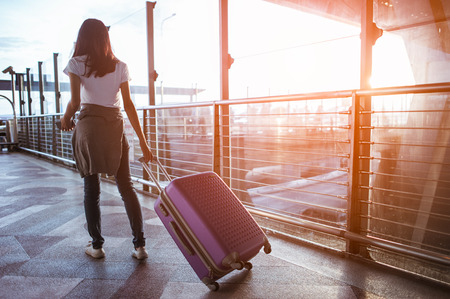 Young woman pulling suitcase in  airport terminal. Copy spaceの写真素材