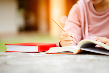 close up of student's hands with books  writing to notebooks.education and school conceptの写真素材