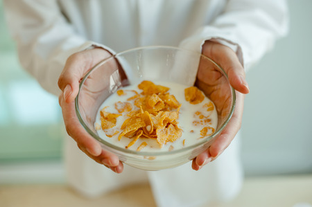 Close Up of Woman' hand holds bowl of cornflakes and milk. Morning concept.Wake up early.Fresh morningの写真素材